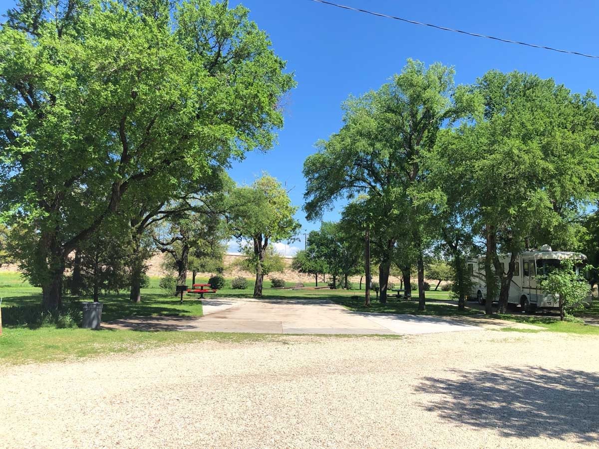 Level concrete pull-through pad between mature shade trees